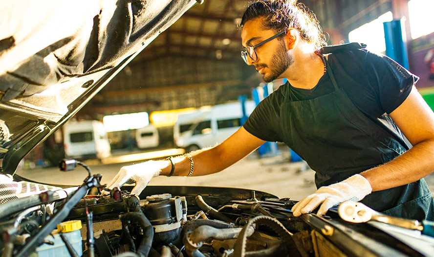 Mechanic with white gloves on working on car engine 