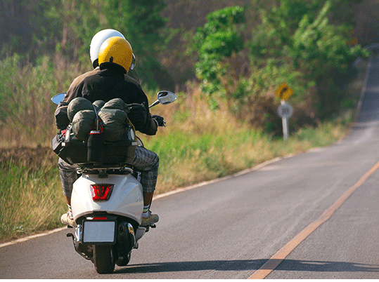 Scooter driving on an empty road with 2 riders 